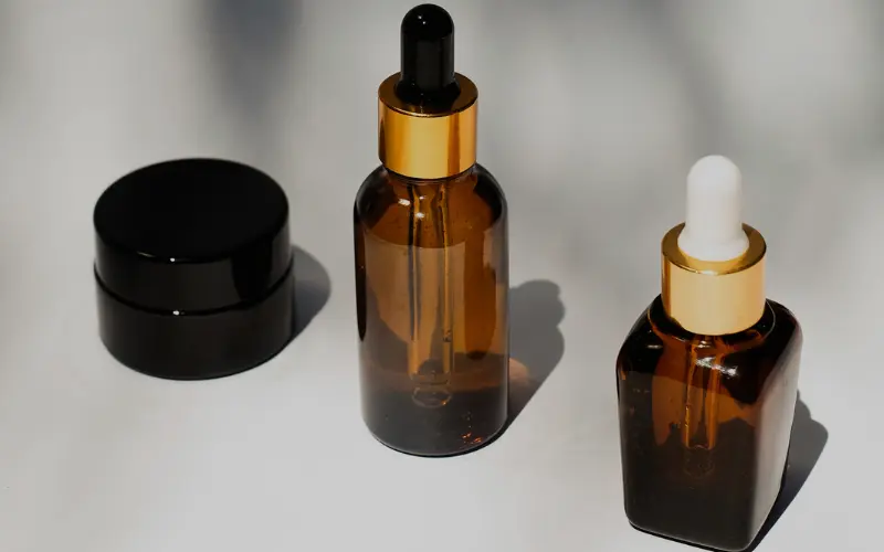 amber dropper bottles and black jar as night skincare routine products for retinol and facial oil before sleep