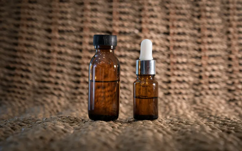 Two amber glass skincare bottles of different sizes showing the price gap between Korean and Western snail mucin products